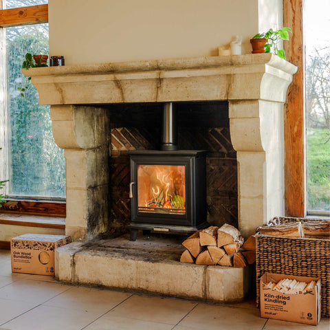 Wood-burning stove in a stone fireplace with Ecofuel firewood and boxes around