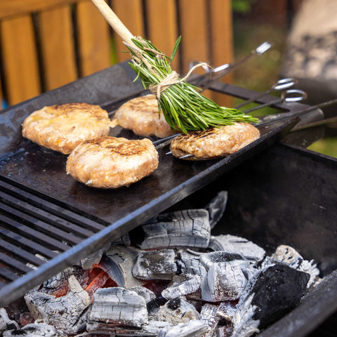 Grilling burgers over ECOFUEL™ Organic Lumpwood Charcoal with rosemary herb brush for added BBQ flavour