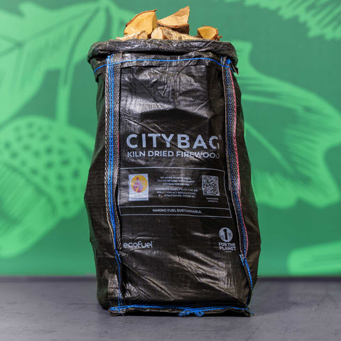 Bag of CityBag kiln dried firewood with a green leafy background
