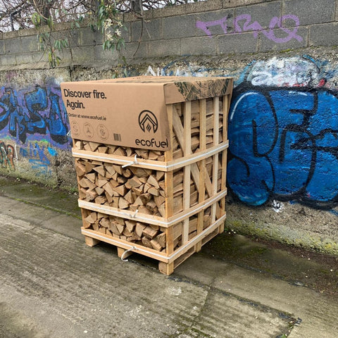 A large crate of firewood stacked and delivered by a graffiti wall 